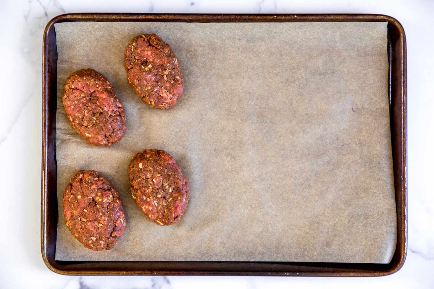 Sheet pan with mini meatloaves ready to be baked.