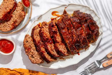 Overhead shot of 5-ingredient meatloaf (sliced) on a white serving plate, with two slices of meatloaf on another plate next to it