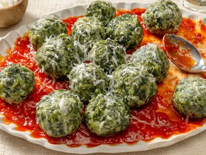 Angled view of a plate of ravioli gnudi over marinara sauce with a spoon