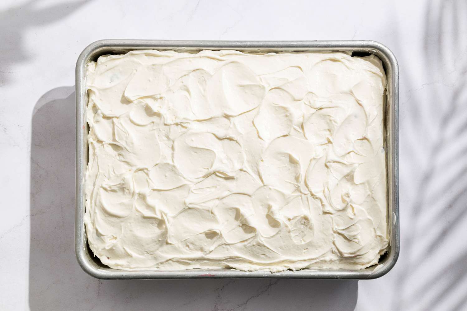 Overhead view of cake in tin, iced with chantilly cream for Easy Berry Chantilly Cake