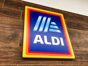A sign with the ALDI logo mounted on a woodentextured wall