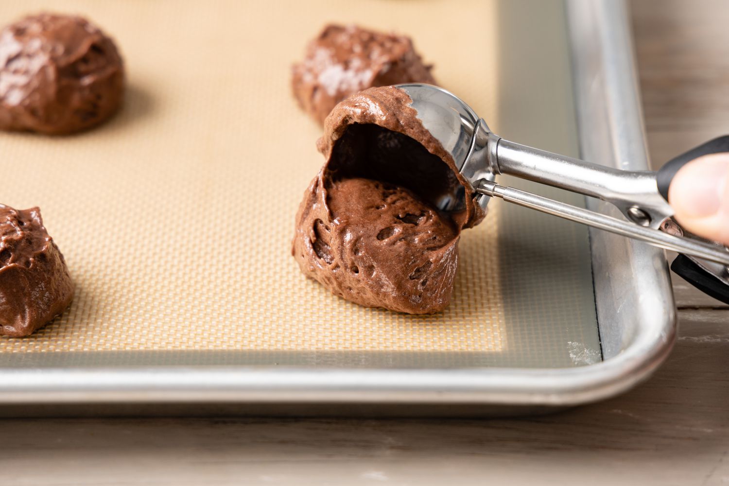 Whoopie Pie Batter Scooped onto a Lined Baking Pan Using an Ice Cream Scoop