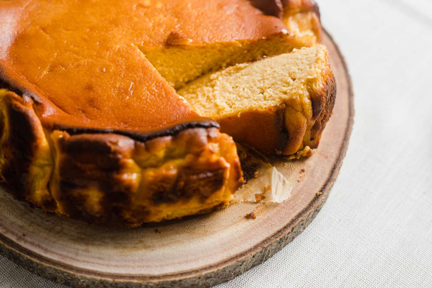 Basque-style cheesecake with slices cut out of it.