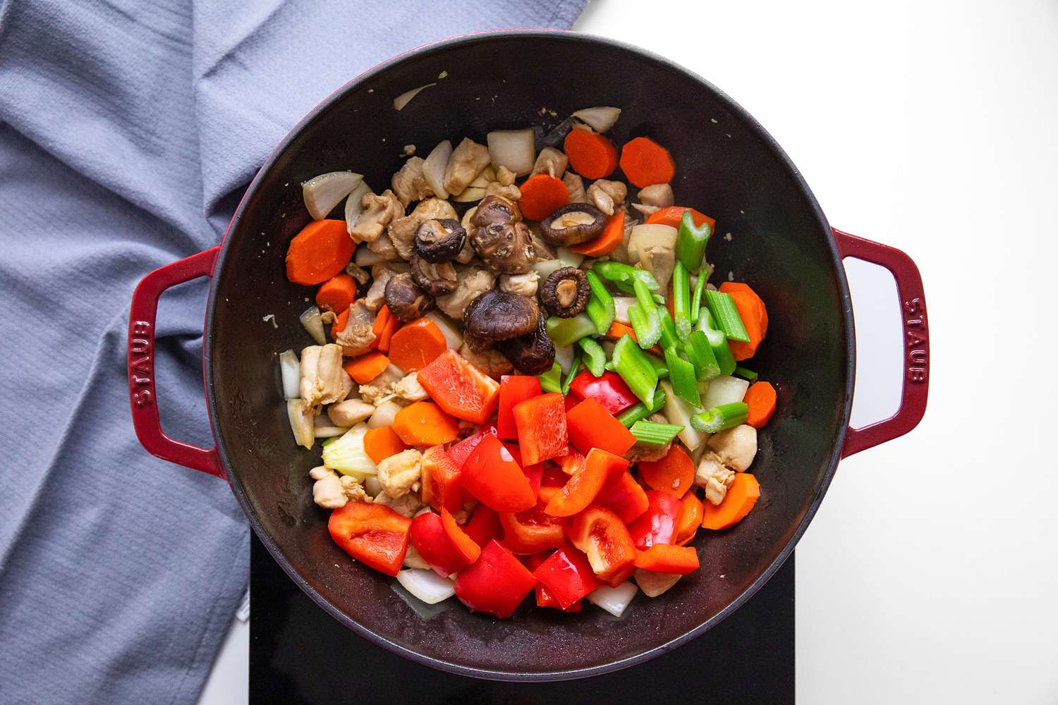 Bell Peppers, Celery, and Shiitake Mushrooms Added to the Wok on a Portable Burner, and Next to It, a Blue Kitchen Towel for Chop Suey Recipe