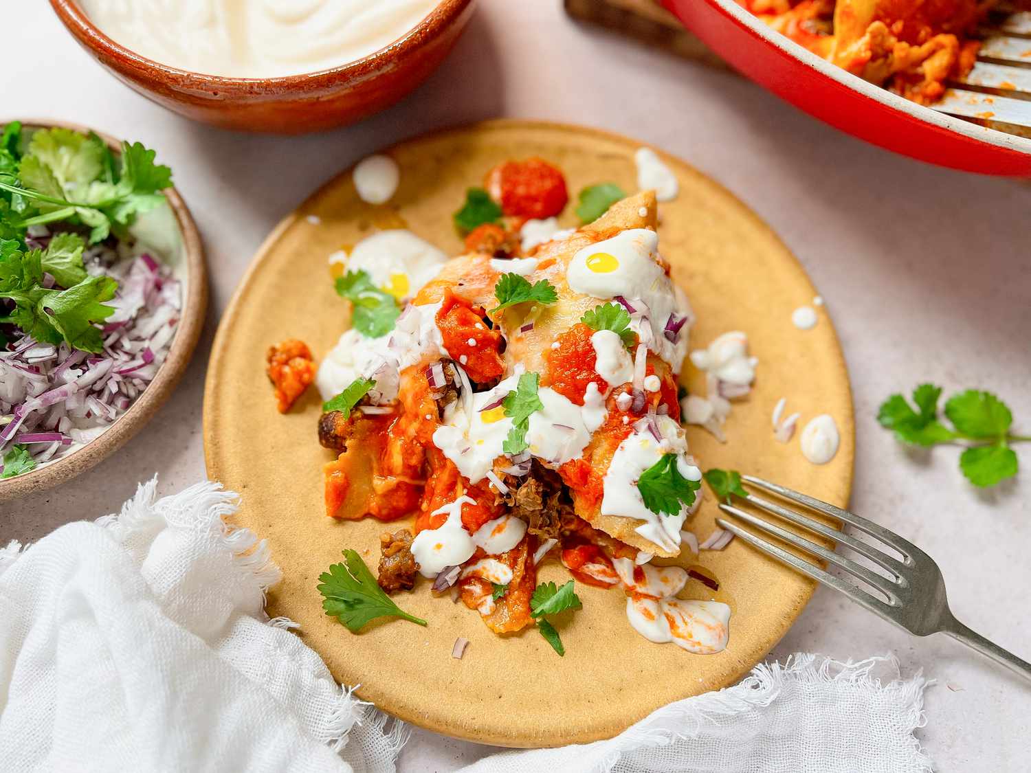 Pulled Pork Enchilada on a Plate Topped with Cilantro, Sour Cream, and Onions