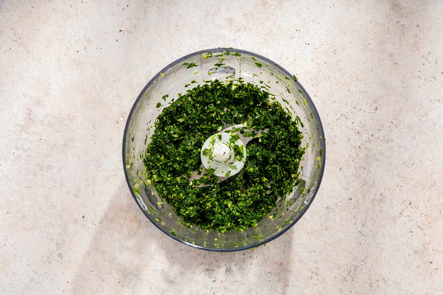 An open food processor with finely chopped garlic and herbs