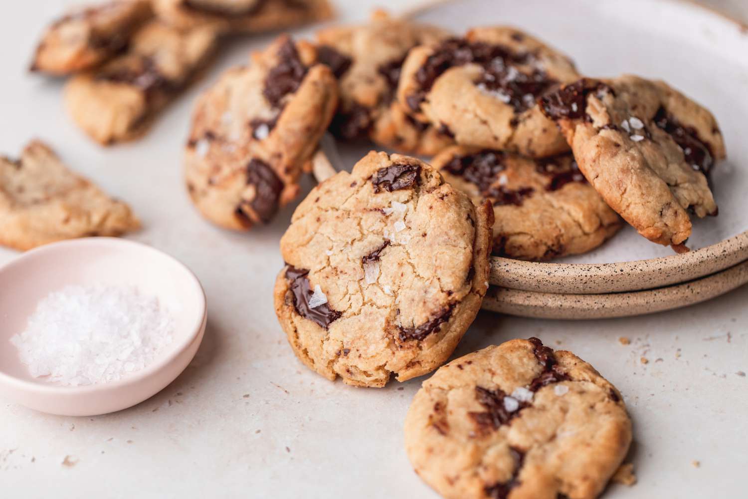 Classic vegan chocolate chip cookies on a plate and scattered on a counter.
