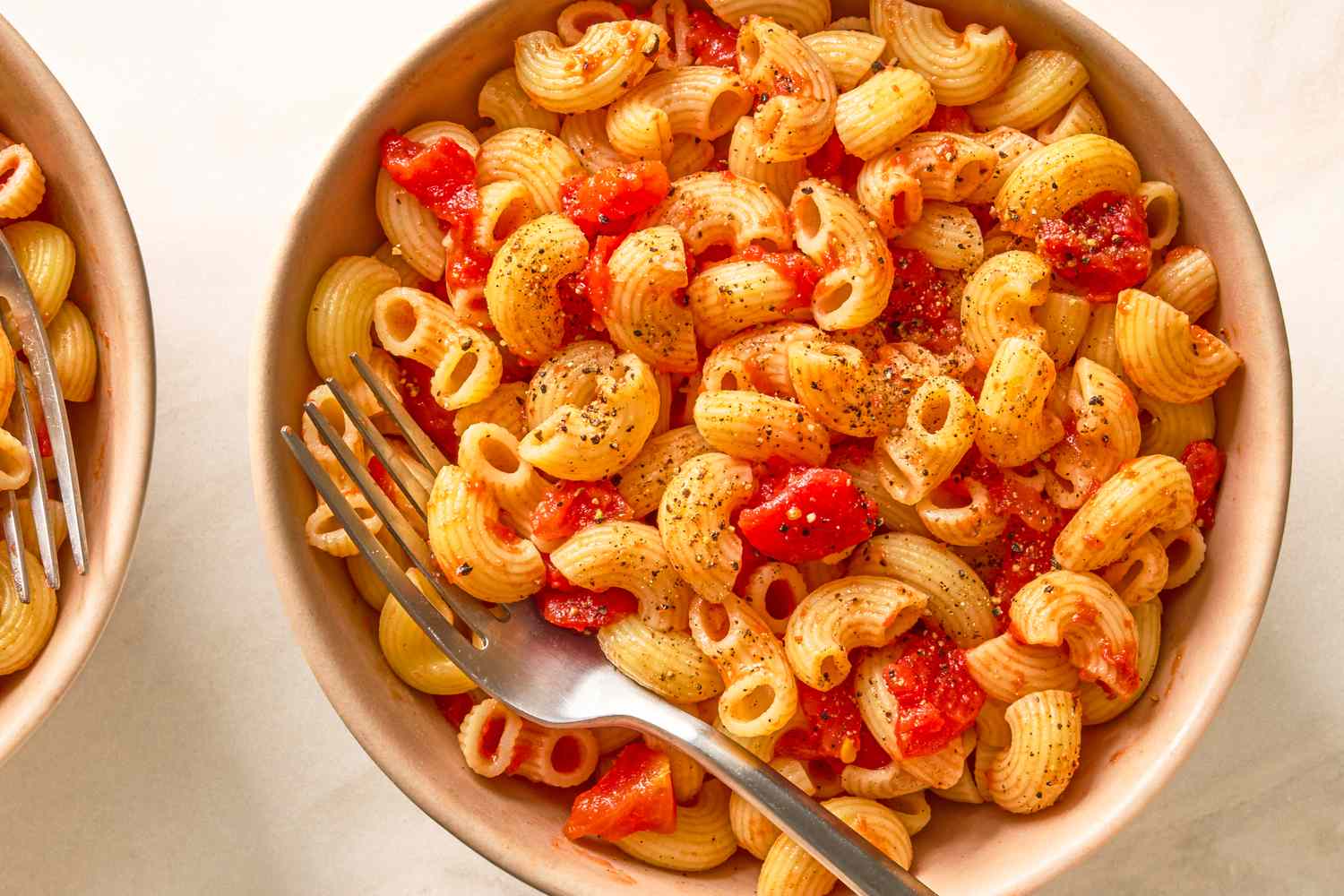 A bowl of pasta with a tomatobased sauce and a fork on the side
