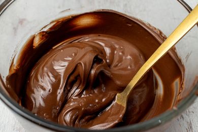 Melted chocolate in a bowl with a gold spoon creamy consistency for baking or cooking