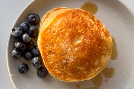 A plate with pancakes blueberries and syrup