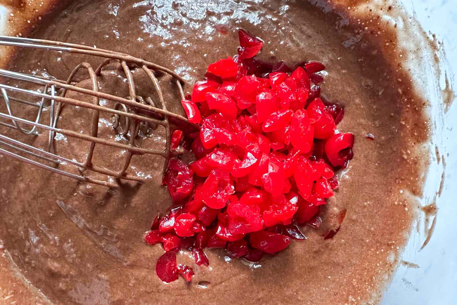 Whisk mixing cherries into chocolate batter