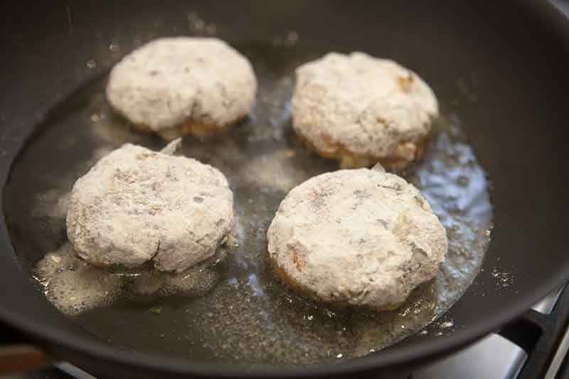 floured shrimp cakes being fried in skillet
