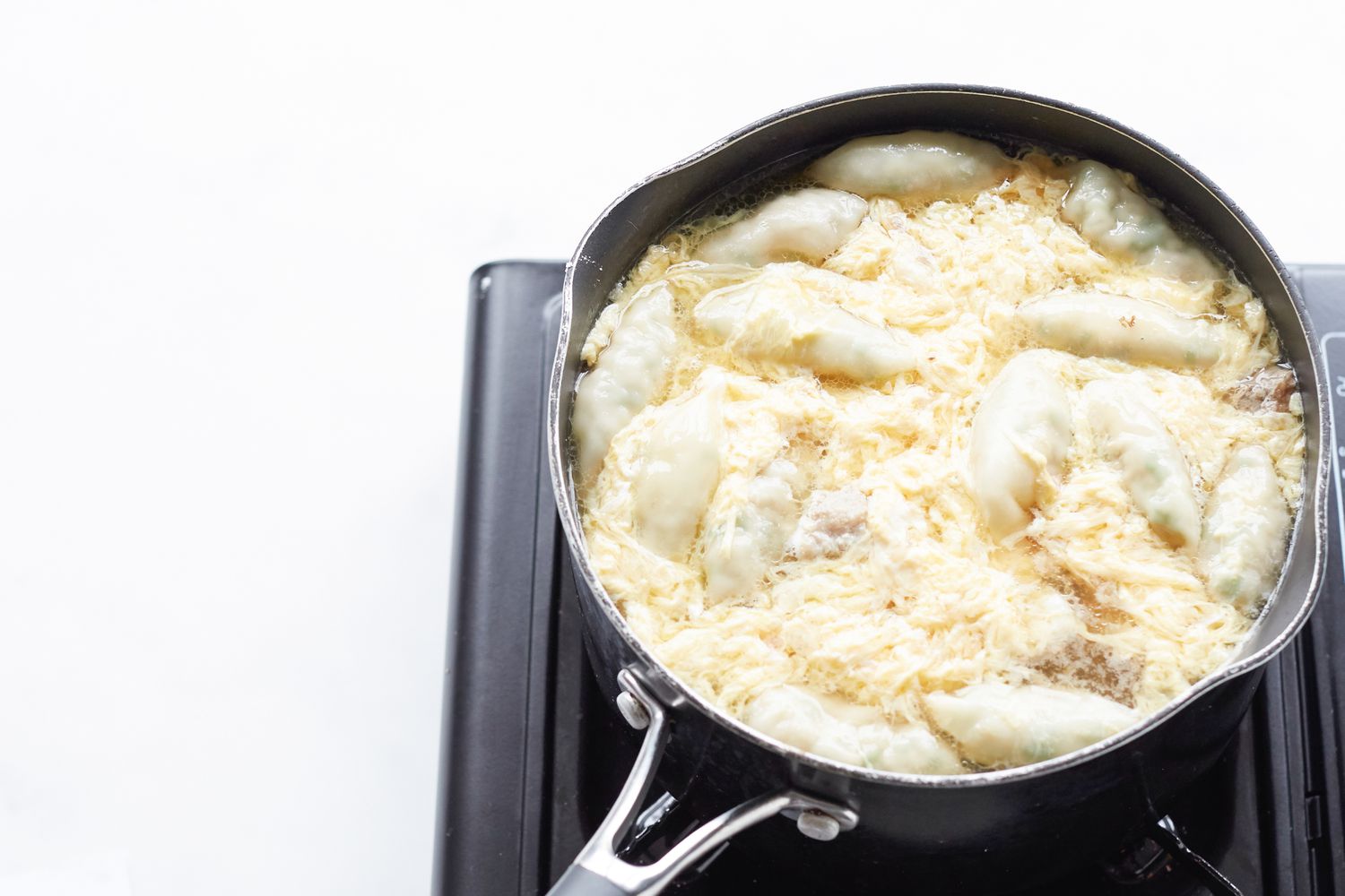 Making Korean dumpling beef soup in a pot on the stove.