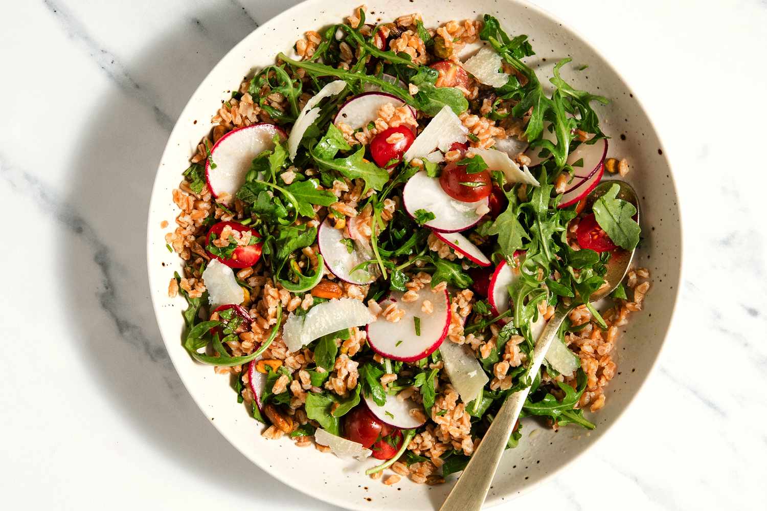 A plate of farro salad with arugula and sliced radishes