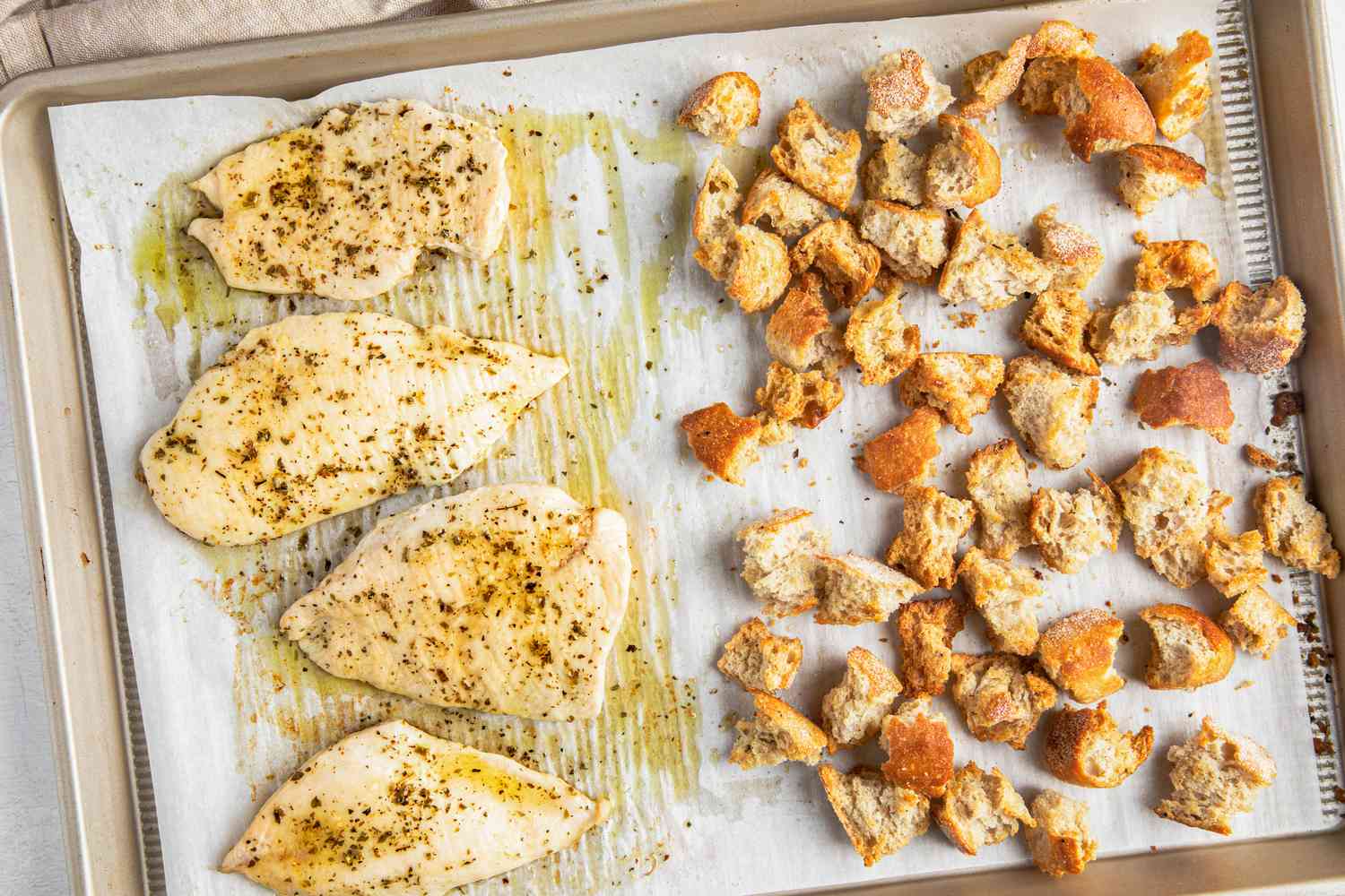 Baked chicken and toasted croutons on the baking sheet for sheet pan caesar salad recipe