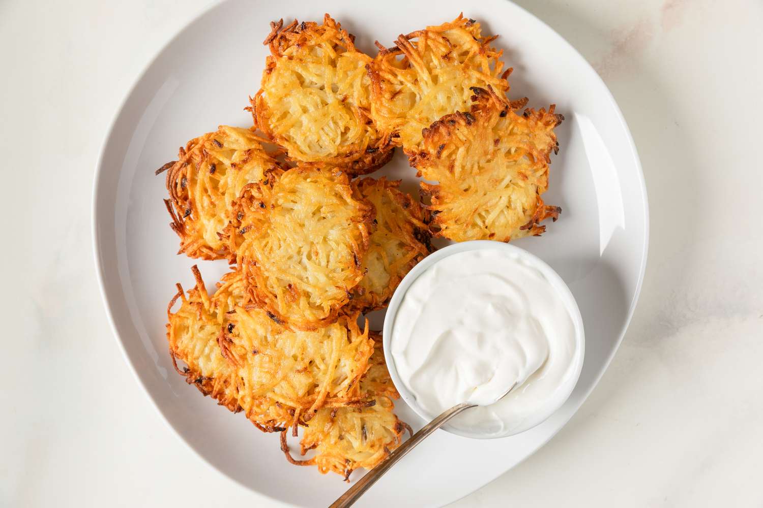 Plate of latkes served with a small bowl of sour cream