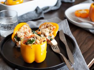 Cheesy rice, tofu, and mushroom stuffed peppers on a black plate