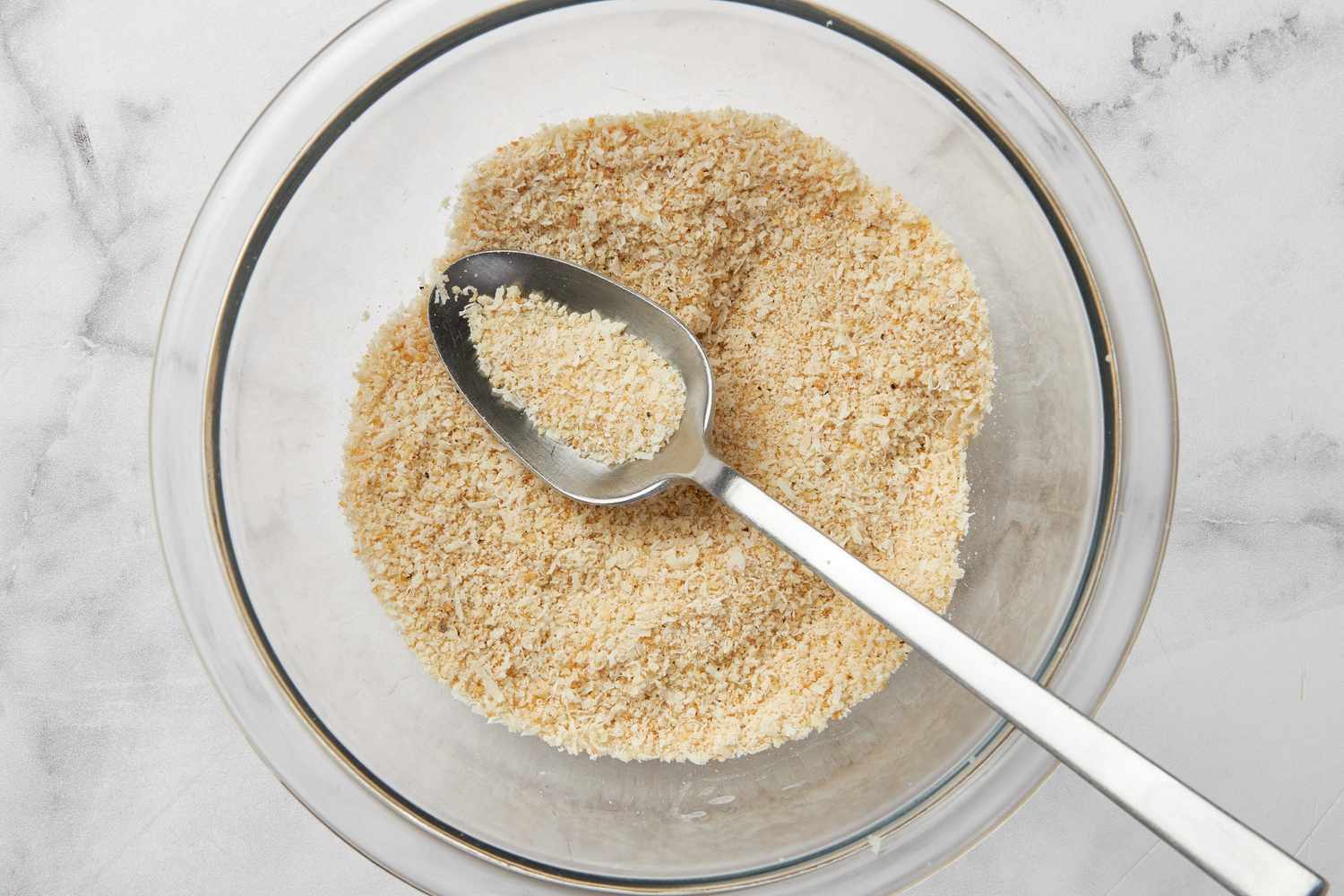 Breading ingredients in a clear bowl with a spoon