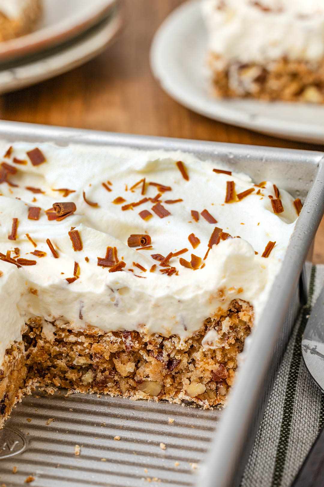Ritz torte in a baking pan (showing cross-section cut), and in the background, a stack of plates and a slice of torte on a plate