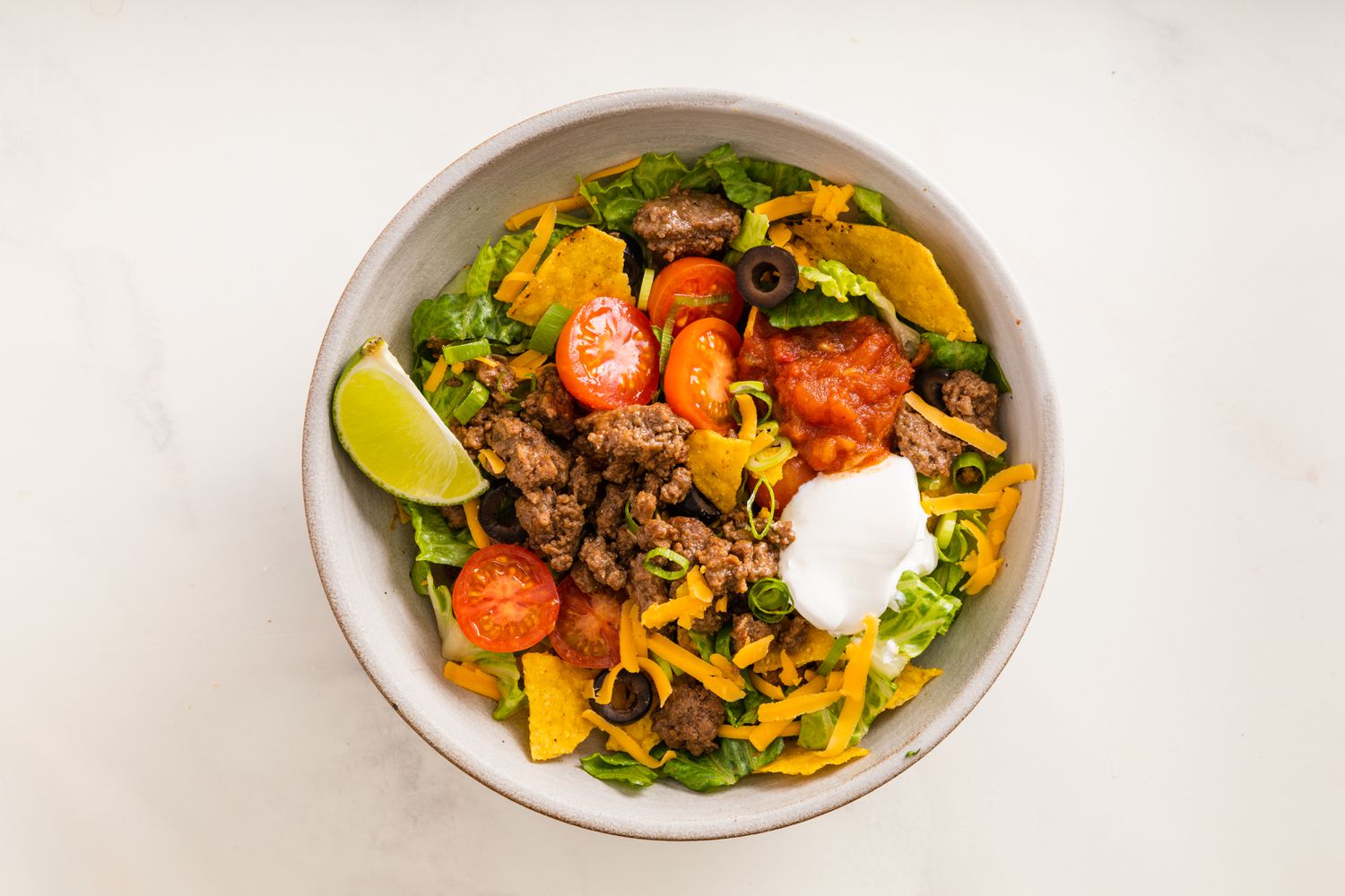 Sliced Grape Tomatoes, Sour Cream, Olives, and a Piece of a Quartered Lime Added to a Bowl