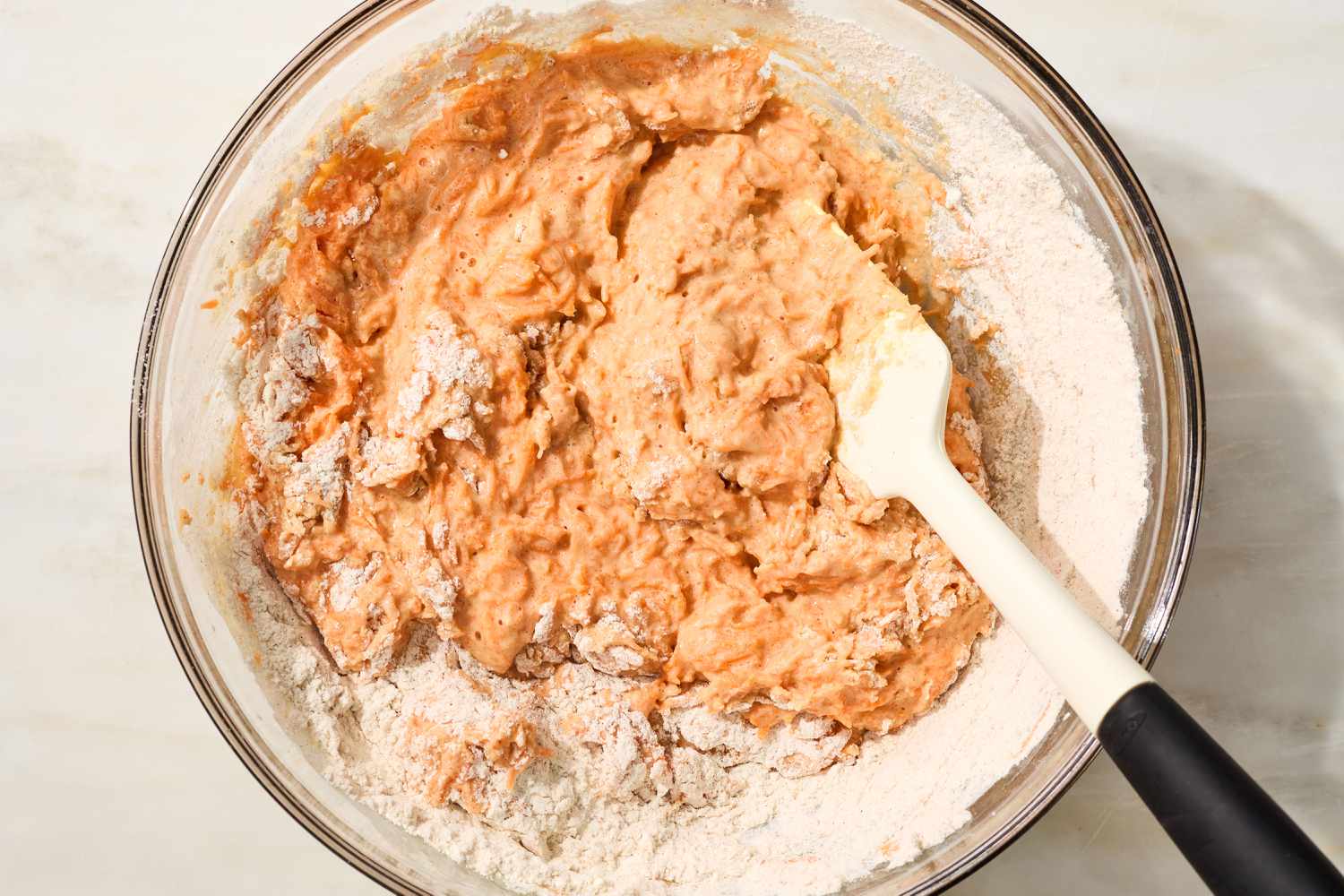 carrot cake waffle batter being mixed with a rubber spatula - wet ingredients into dry