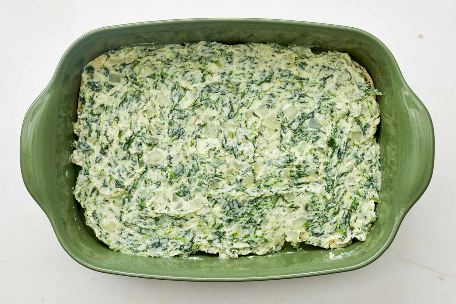 Spinach and cheese filling added to a casserole dish for spinach flornetine breakfast casserole 
