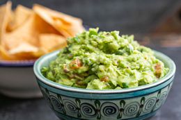 Guacamole in a blue and white bowl, served with tortilla chips