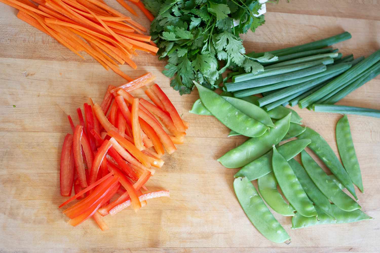 Vegetables on a cutting board for a vegetable rice noodle salad.
