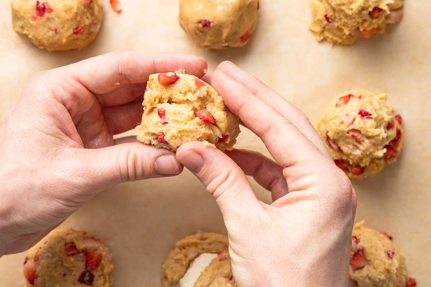 Sealing the cheesecake filling inside the strawberry cookie dough