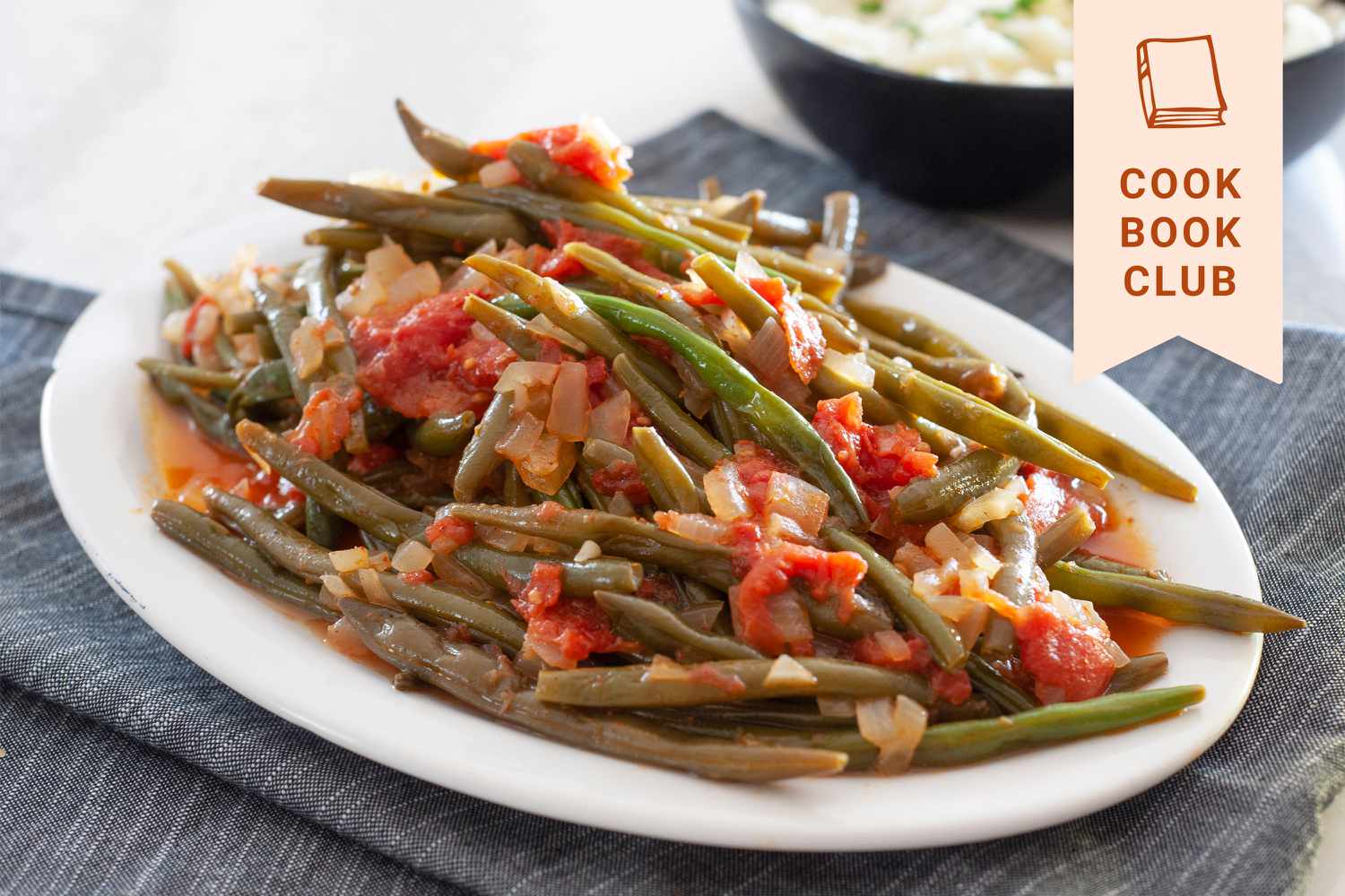 Side view of braised green beans on an oval platter.