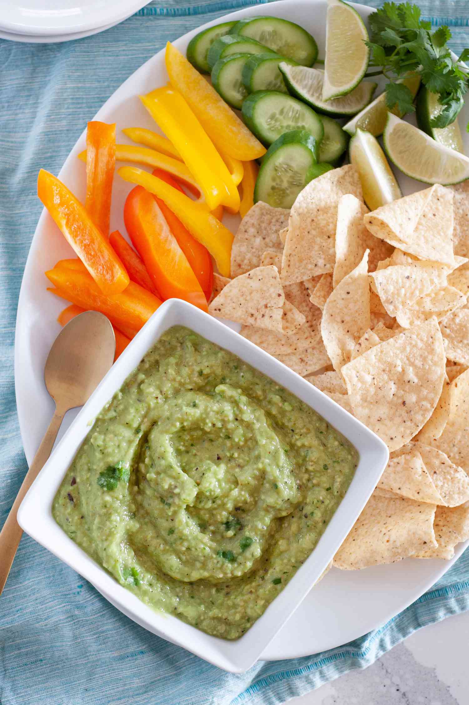 Bowl of Tomatillo Avocado Salsa on a Platter of Chips and Vegetables