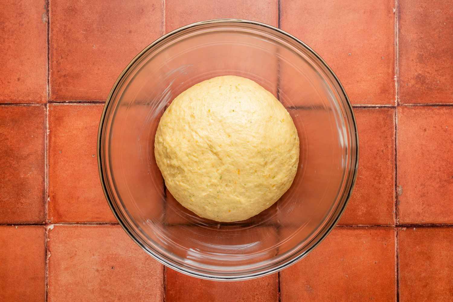 Pan de muerto dough resting in a buttered bowl for pan de muerto recipe