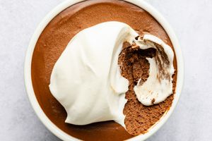 Mocha mousse in a bowl with whipped topping, a portion scooped out