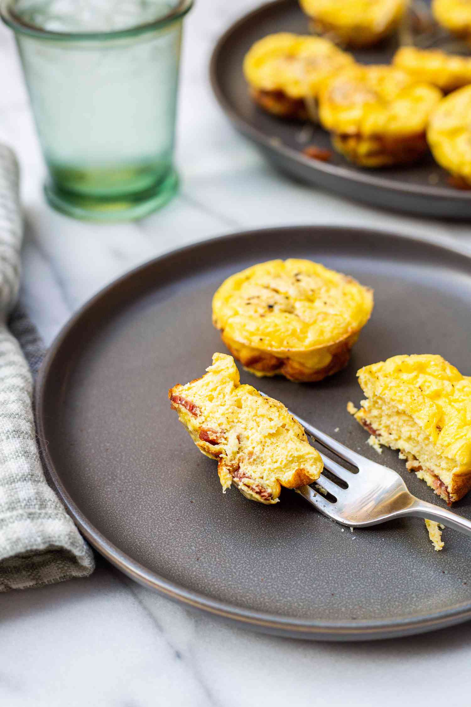 A Serving of Bacon and Gruyère Egg Bites on a Plate with Cut in Half with a Fork