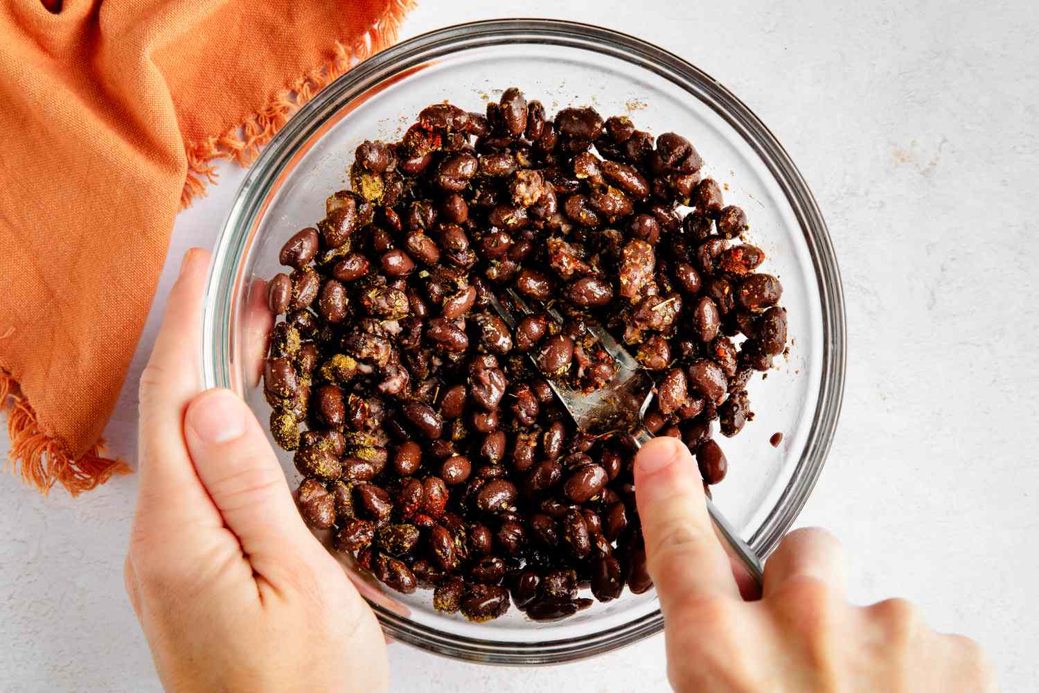 Bowl of beans mashed together using a fork for black bean toast