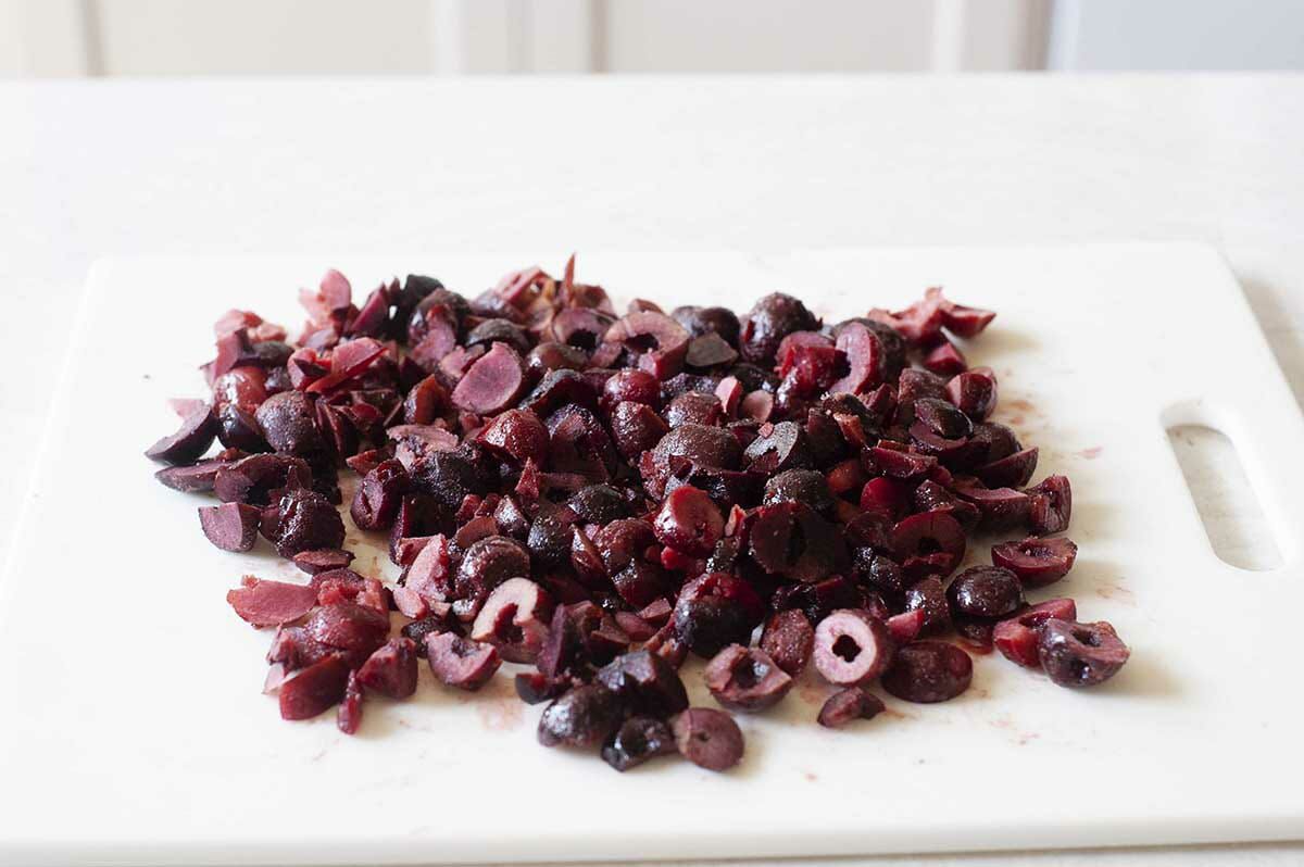 Chopped cherries on a white cutting board for Cherry Chocolate Cake with Whipped Cream.