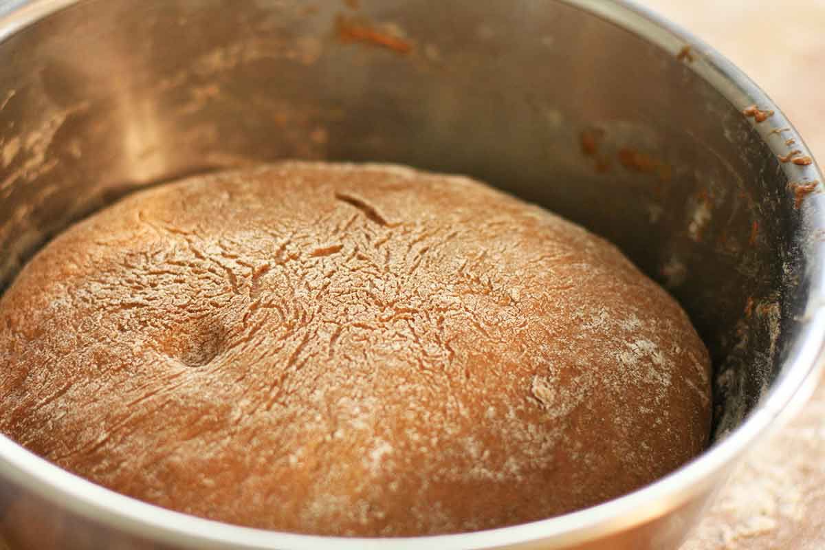 Risen rye bread dough in a metal bowl