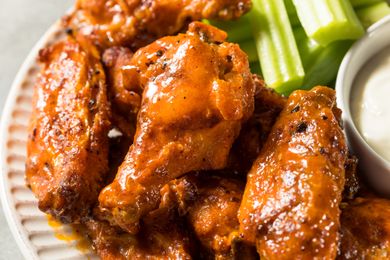 Buffalo chicken wings on a plate with celery sticks and a bowl of dip