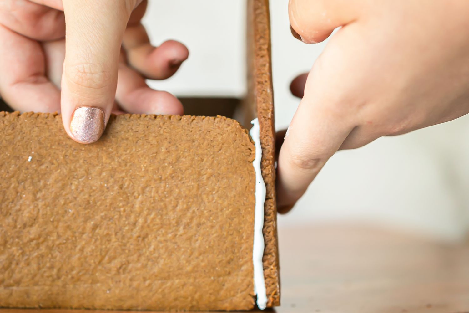 Putting the pieces of a gingerbread house together to show how to make a gingerbread house.