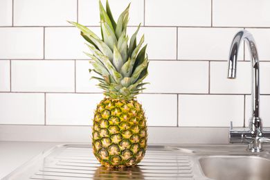 Pineapple on a kitchen countertop next to a sink