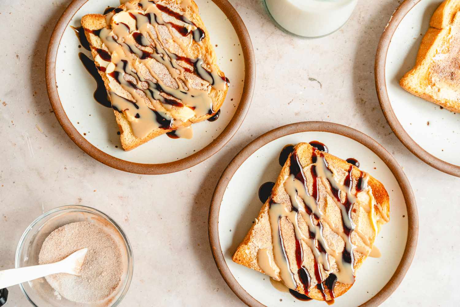 3 plates of Tahini Cinnamon Toast, cinnamon sugar on the side and a glass of milk