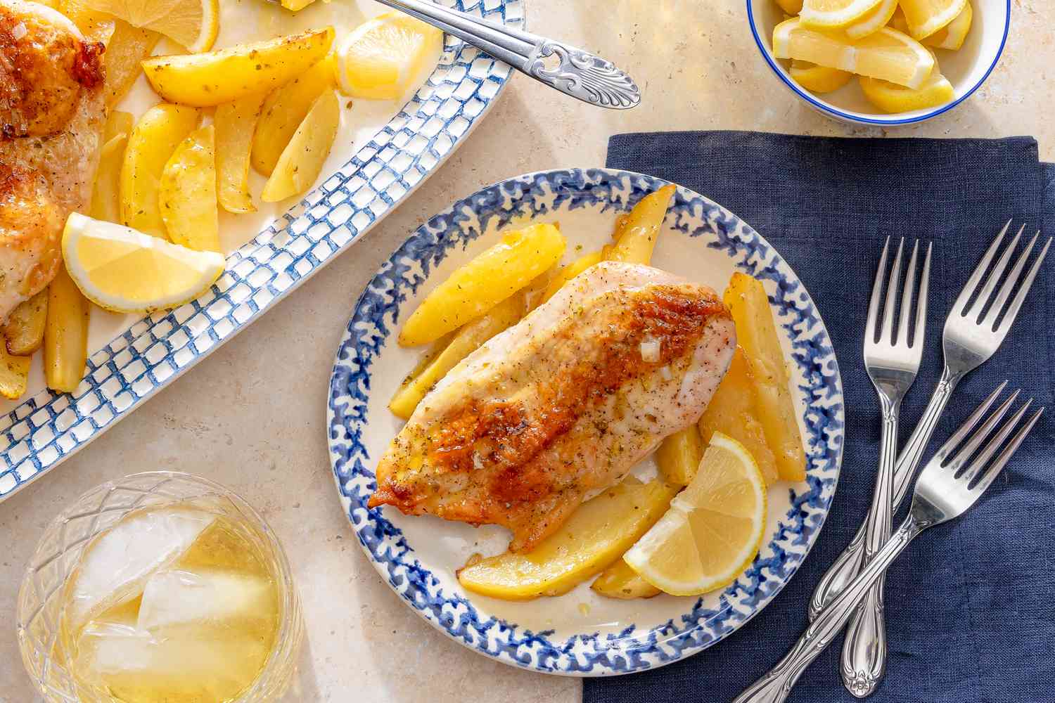 Greek-Style Lemon Chicken and Potatoes on a plate with forks and napkins