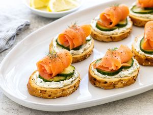 Smoked salmon, cucumber, and cream cheese crostini on a platter.