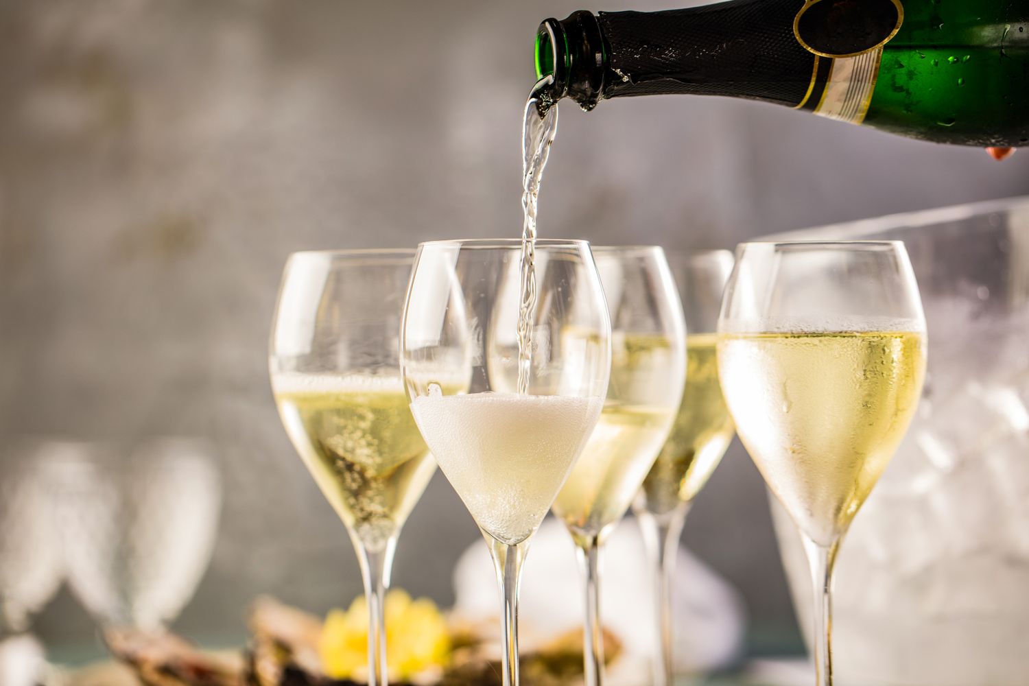 Champagne being poured into a glass with other filled and partially filled glasses in the background on a festive table