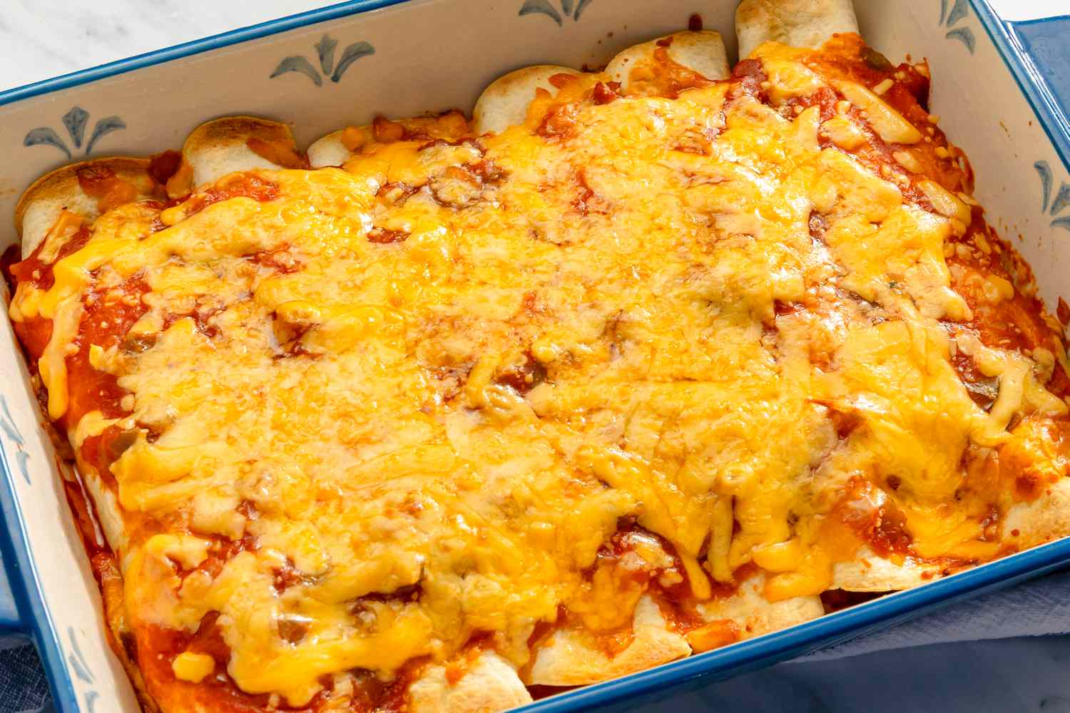 Baked tortilla dish topped with melted cheese in a casserole dish
