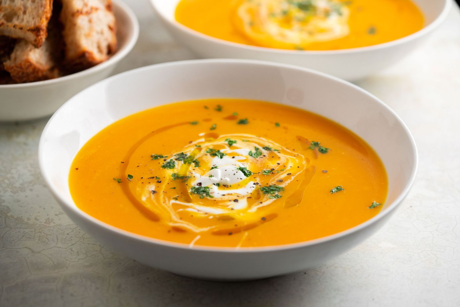 Creamy Tomato soup in a bowl garnished with herbs, cream, and sauces