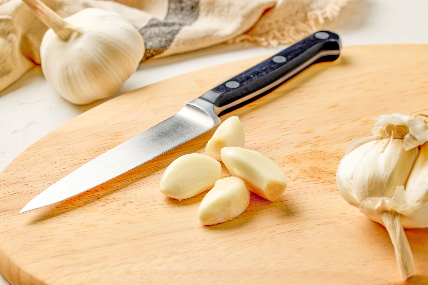 Garlic cloves and a knife on a wooden cutting board