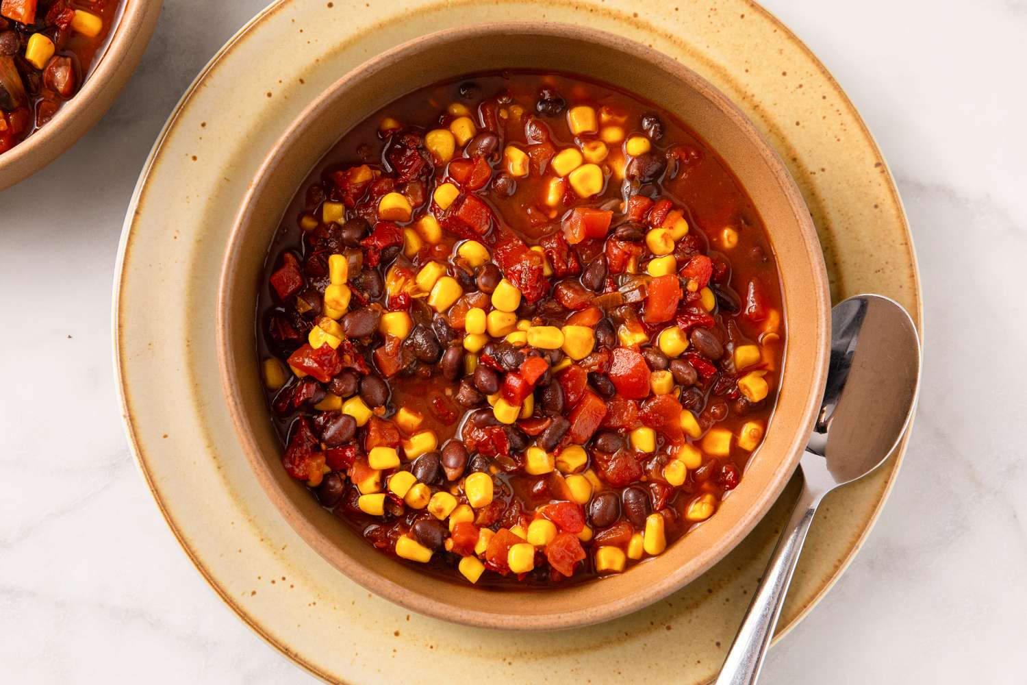 A bowl of chili with black beans corn and diced tomatoes