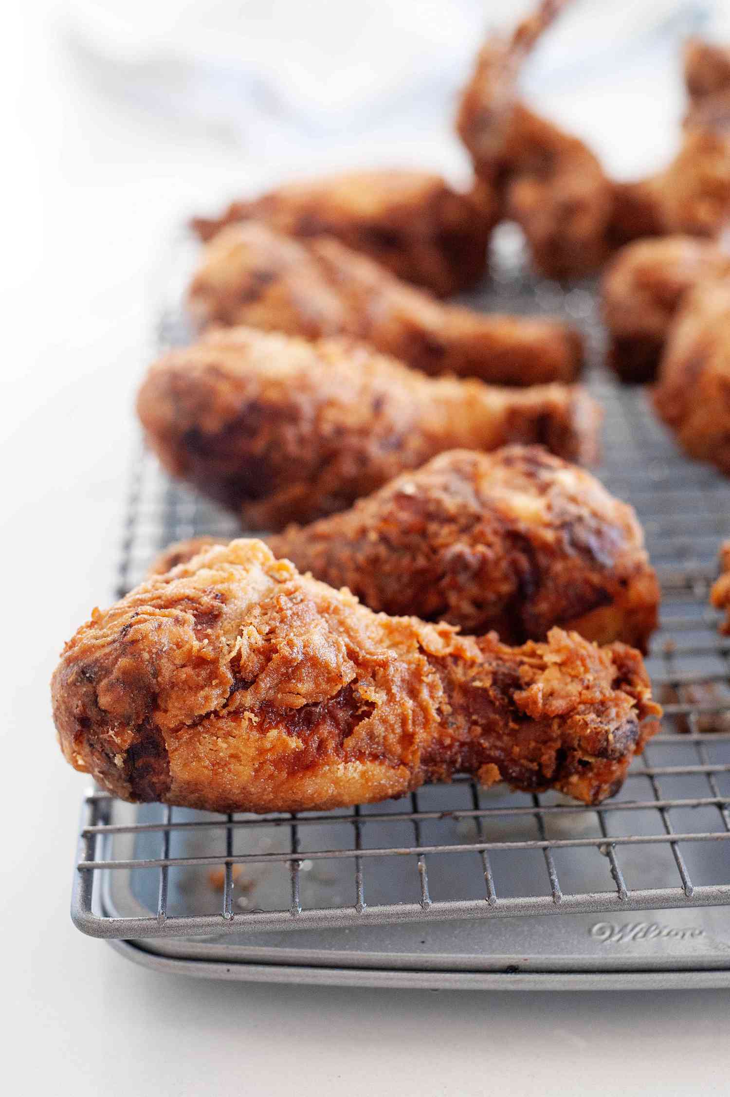 Side view of buttermilk fried chicken on a cooling rack.