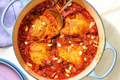 Overhead view of a blue dutch oven of finished Country Captain Chicken recipe on a white background